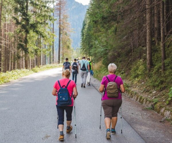Morske oko, Poland - September 12, 2019: group of people walking by trail seniors with sticks hiking concept